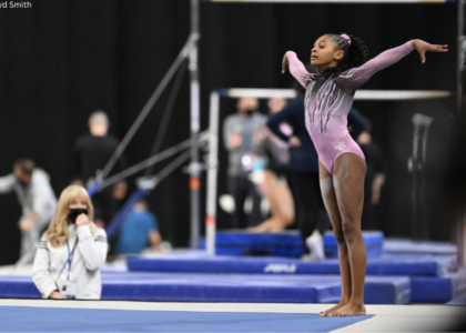 Ariana Barksdale stands in the corner of the floor with both arms up.
